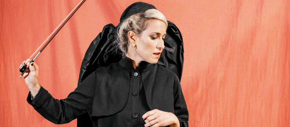 Julia Lacherstorfer mit Kopftuch, schwarzem Kleid und Geigenbogen