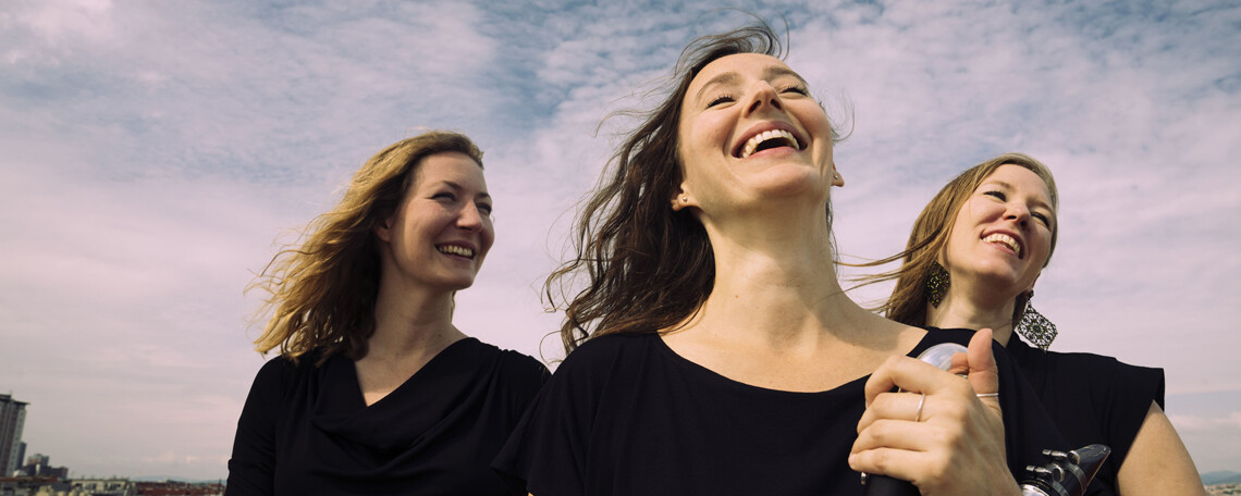 Die 3 Musikerinnen von Mister Montelli lachend vor bewölktem Himmel