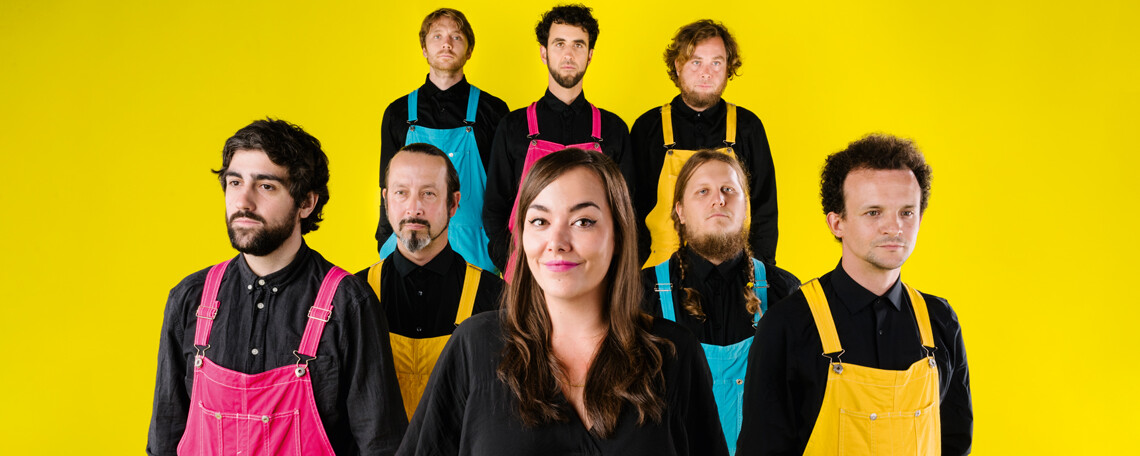 Yasmo und die 7 Musiker der Klangkantine vor gelbem Hintergrund